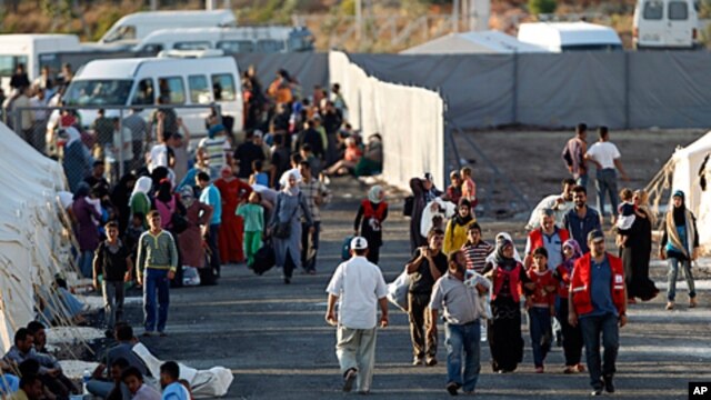 Newly-arrived Syrian refugees walk to their tents in the Turkish border town of Reyhanli in Hatay province, as others who are already placed rest in front of their tents (File)