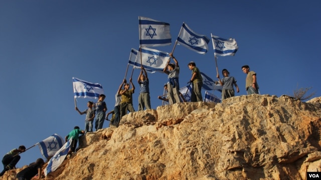 Children in the West Bank settlement of Itamar wave Israeli flags on a hilltop. (file) (VOA/Rebecca Collard)
