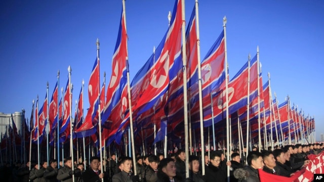 朝鲜人手举国旗在平壤金日成广场游行向朝鲜劳动党表忠诚.(2016年2月25日)