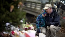 December 16: David Freedman, right, kneels with his son Zachary, 9, as they visit a sidewalk memorial for the 26 people, including 20 children, who were killed at Sandy Hook Elementary School in Newtown, Connecticut.