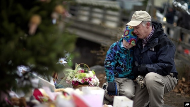 December 16: David Freedman, right, kneels with his son Zachary, 9, as they visit a sidewalk memorial for the 26 people, including 20 children, who were killed at Sandy Hook Elementary School in Newtown, Connecticut.