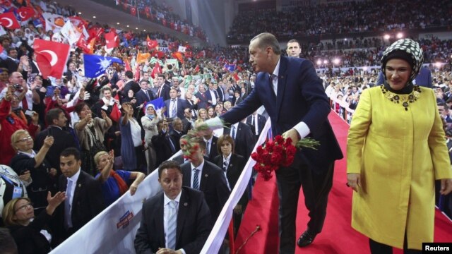 Turkey's PM and leader of ruling Justice and Development Party (AKP) Tayyip Erdogan, accompanied by his wife Emine Erdogan (R), throws carnations to supporters during his party congress in Ankara, September 30, 2012.