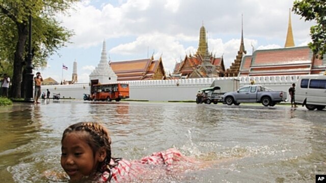 A girl swims in the floodwater in front of Bangkok's Grand Palace in a riverside neighborhood, Thailand.