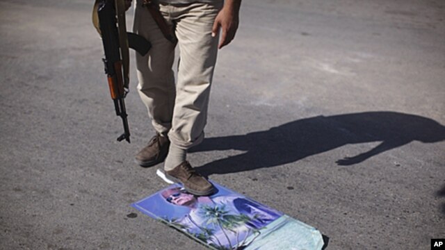 A rebel fighter steps over a calendar with Moammar Gadhafi's picture at a checkpoint in Tripoli, Libya, July 30, 2011