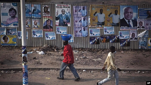 Pedestrians walk past election posters in Democratic Republic of Congo's capital Kinshasa, November 25, 2011.