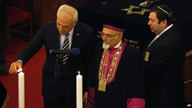 Turkey's Chief Rabbi Izak Haleva (C) and Istanbul Governor Huseyin Avni Mutlu (L) light candles, in memory of holocaust victims, during a commemoration to mark International Holocaust Remembrance Day at Neve Shalom Synagogue in Istanbul, January 26, 2012.