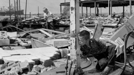 This Aug. 19, 1969 photograph showing Carl Wright, 11, drinking from a broken pipe amid the ruins of his father's service station in Gulfport, Miss., in the aftermath of Hurricane Camille.