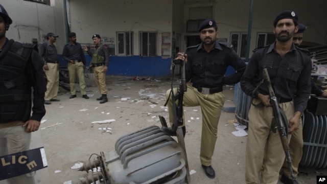 Pakistani police officers stand guard at the office of local electrical company attacked by angry protesters to condemn  electricity shortages in Lahore, March 2012. 