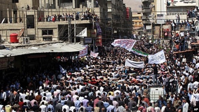 Syrians wave Islamic and revolutionary flags at a large protest in Douma, a suburb of Damascus, April 20, 2012.