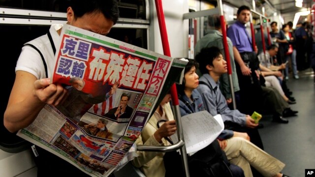 Một hành khách trên một chuyến xe điện ngầm ở Hong Kong đọc nhật báo có đăng các bài về bầu cử tổng thống ở Mỹ