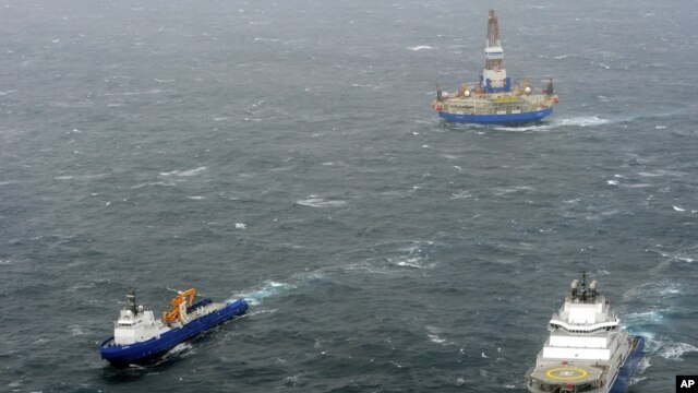 In this photo provided by the United States Coast Guard, the tugs Aiviq and Nanuq tow the mobile drilling unit Kulluk while a Coast Guard helicopter from Air Station Kodiak transports crew members on Dec. 29, 2012, 80 miles southwest of Kodiak City, Alaska.