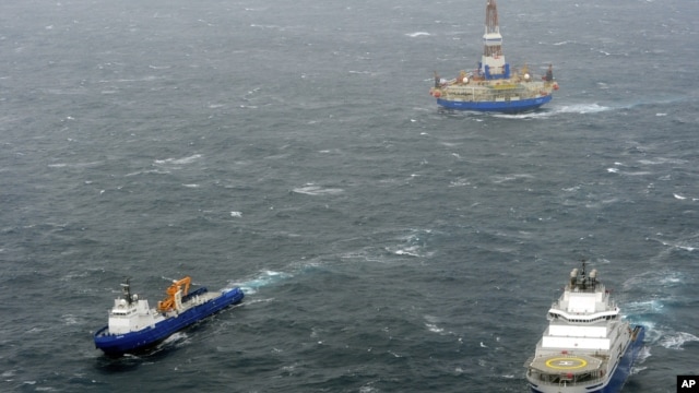 In this photo provided by the United States Coast Guard, the tugs Aiviq and Nanuq tow the mobile drilling unit Kulluk while a Coast Guard helicopter from Air Station Kodiak transports crew members on Saturday, Dec. 29, 2012, 80 miles southwest of Kodiak C