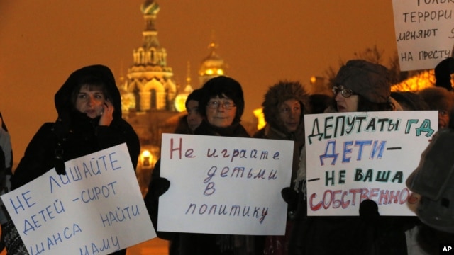 Opposition activists hold posters reading "Do not involve children in politics" and "Lawmakers, children are not your  ownership" during a protest against a bill banning U.S. adoptions of Russian children in St. Petersburg, Russia,  December 26, 2012.