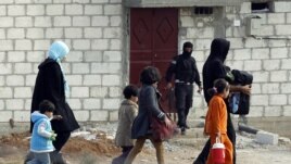 People from the northern Syrian town of Ras al-Ain attempt to cross into Turkey, as a Free Syrian Army fighter leaves a home in the background, as seen from the Turkish border town of Ceylanpinar, Sanliurfa province, November 13, 2012.