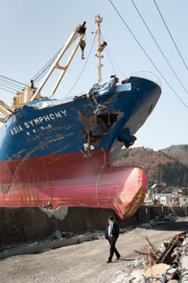 A man walks past a huge ship that breached a seawall in Kamaichi, Japan