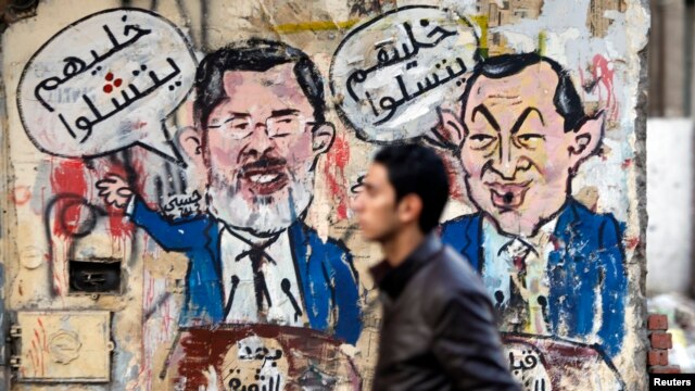 A protester walks past a graffiti during a march at Tahrir Square in Cairo, February 11, 2013. The march, was organized by Egyptians who oppose Egypt's President Mohamed Morsi and members of the ruling Muslim Brotherhood on the second anniversary of the r