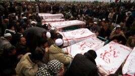 Shi'ite Muslims sit around coffins of victims killed in Saturday's bomb attack, during a funeral at a cemetery in Quetta, February 20, 2013. 