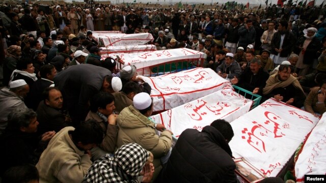 Shi'ite Muslims sit around coffins of victims killed in Saturday's bomb attack, during a funeral at a cemetery in Quetta, February 20, 2013. 