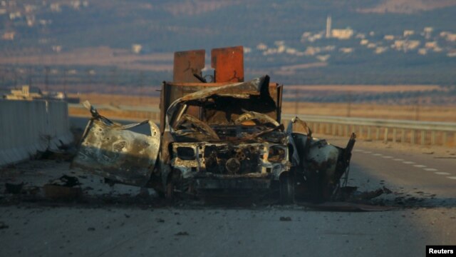 FILE - A damaged military vehicle is seen along a road in Freikeh village after fighters from an Islamist coalition took control of the village from forces loyal to Syria's President Bashar al-Assad in Idlib, Syria, July 30, 2015.