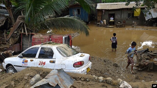 Residents stand in floodwaters after flash floods brought by Typhoon Washi struck Iligan city in the southern Philippines, December 17, 2011.