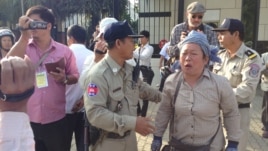 Police ask an activist to stand near the U.S. embassy and wait for officials to receive her petition that calls for U.S. intervention to release union leaders and workers arrested in early January, Phnom Penh, Jan. 21, 2014. (Heng Reaksmey/VOA)
