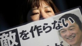 Một phụ nữ cầm biểu ngữ với hình của nhà báo Goto trước tư gia của Thủ tướng Nhật Bản tại Tokyo, ngày 1/2/2015.