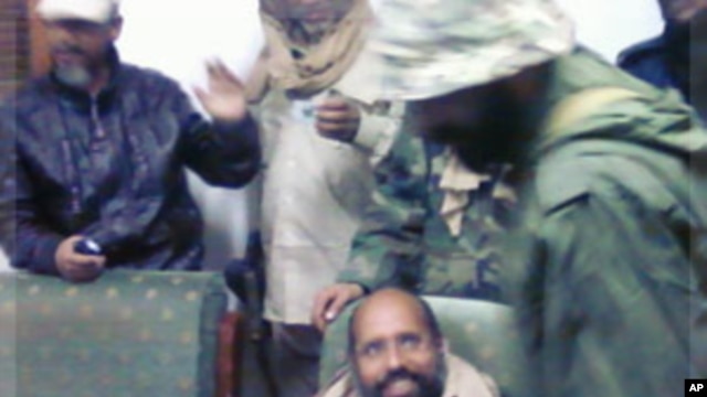 Saif al-Islam Gaddafi sitting with his captors in Obari airport November 19, 2011. Saif al-Islam has been captured in Libya's southern desert, scared and with only a handful of supporters