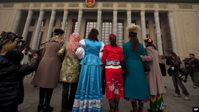 Uighur ethnic minority delegates in their traditional dresses pose for photos as they walk towards the Great Hall of the People for the opening session of the annual National People's Congress in Beijing, China, March 5, 2012. 