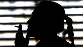 FILE - A woman smokes a cigarette in a parking lot in Bangkok, Thailand, May 27, 2010.