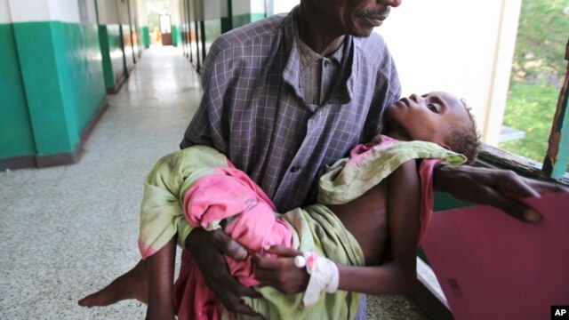 An man carries his malnourished child through the corridors inside Banadir hospital in Somalia's capital, Mogadishu, Aug. 9, 2011. (Reuters)