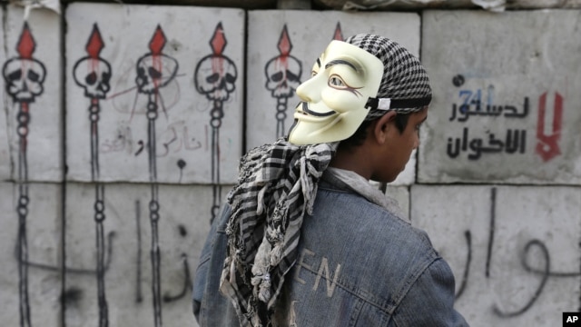 A protester looks at graffiti on cement blocks in front of the presidential palace in Cairo, Egypt, December 16, 2012. 