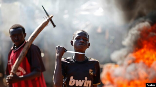 FILE - A boy gestures in front of a barricade on fire during a protest after French troops opened fire at protesters blocking a road in Bambari May 22, 2014. 