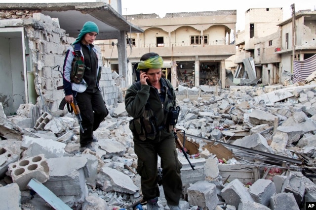 FILE - Kurdish female fighters move to another secured point in the contested zone of Kobani, Syria, on Nov. 19, 2014.