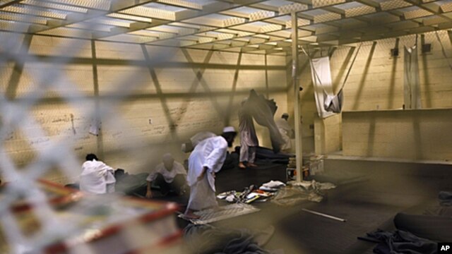 Afghan detainees, seen through a mesh wire fence, prepare for noon prayers inside the Parwan detention facility near Bagram Air Field in Afghanistan, March 23, 2011.