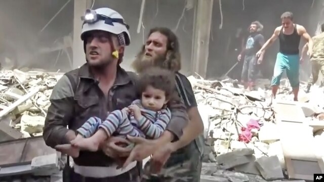 Ảnh chụp từ video được đăng tải trên mạng Validated UGC cho thấy nhân viên cứu hộ đang mang một đứa trẻ ra khỏi khu vực bị tấn công ở Aleppo, Syria, ngày 28/4/2016. 
