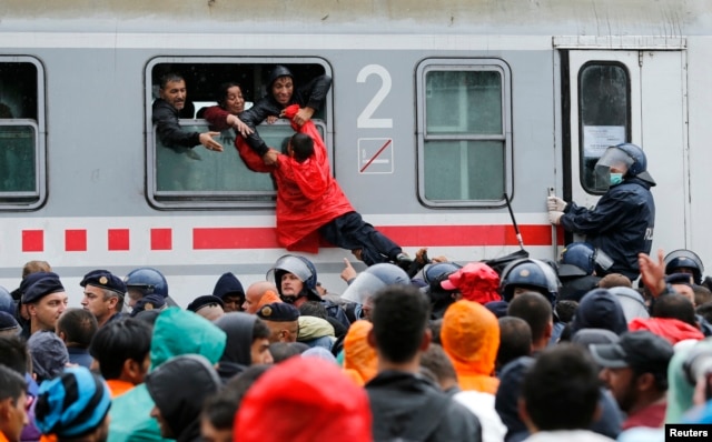 Một cậu bé được kéo lên qua cửa sổ đoàn tàu ở nhà ga Tovarnik, Croatia, ngày 20 tháng 9, 2015.