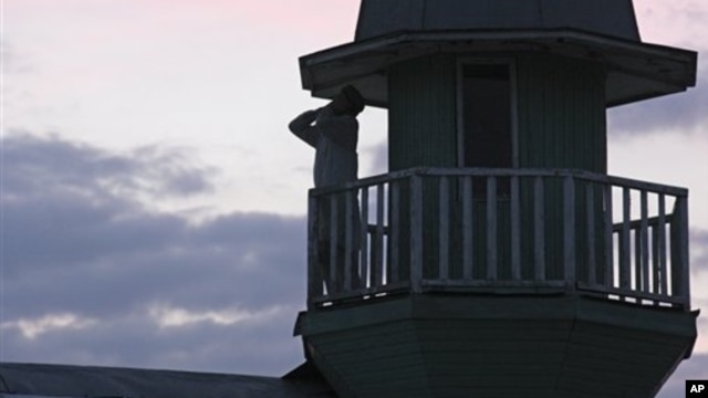 Member of Islamic sect calls for evening prayer from atop the house where followers lived in seclusion, Kazan, Russia, Aug. 9, 2012.