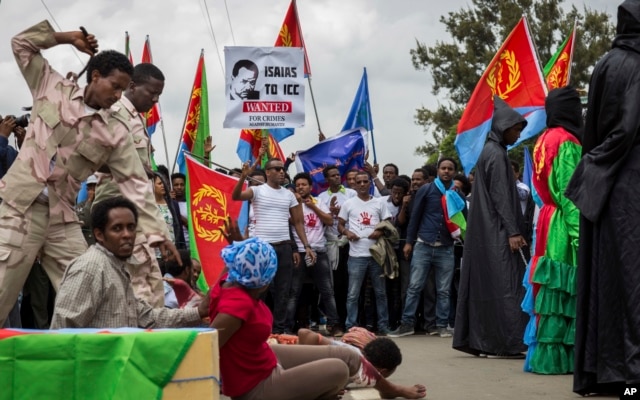 Eritrean refugees and dissidents, some holding Eritrean flags and some dressed as Eritrean military to illustrate beatings and torture, left, demonstrate outside the headquarters of the African Union in Addis Ababa, Ethiopia, June 23, 2016.