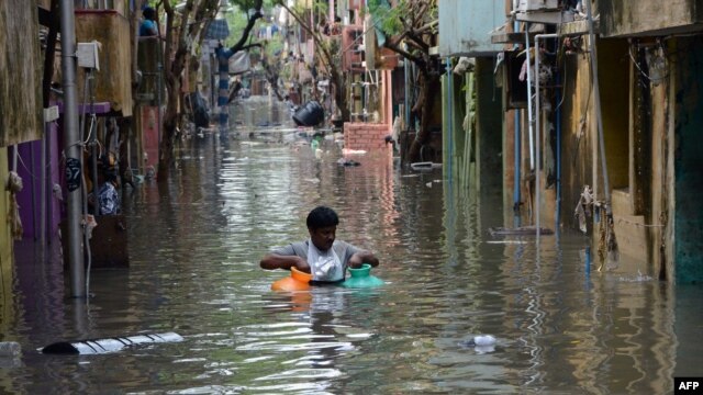 Một người đàn ông mang bình gas trong nước lũ ở Chennai, Ấn Độ, ngày 4/12/2015.