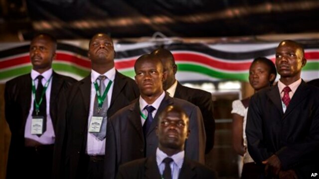 Security and bodyguards of the election commission chairman stand as he delivers a statement to the media, at the National Election Center