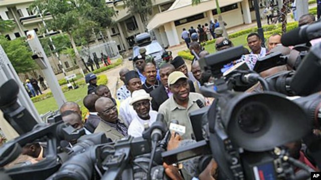 Nigeria's president Goodluck Jonathan (center right) fields questions from journalists as he leaves U.N. headquarters, where a day earlier a suicide bomber crashed through an exit gate and detonated a car full of explosives, in Abuja, Nigeria, August 2011