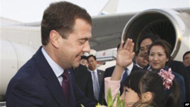 A Chinese girl greets Russia President Dmitry Medvedev, left,  upon his arrival at the Beijing Capital International Airport Sunday, Sept. 26, 2010.