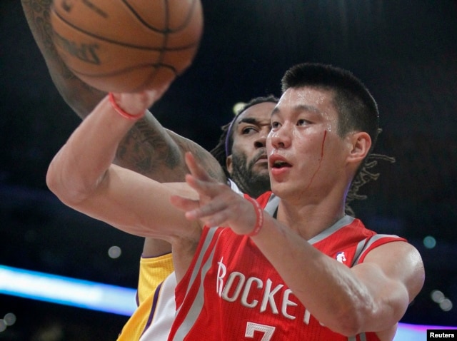 Houston Rockets point guard Jeremy Lin comes under the basket against Los Angeles Lakers center Jordan Hill (27) during their NBA basketball game in Los Angeles, California, Nov. 18, 2012.