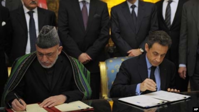 France's President Nicolas Sarkozy (R) and Afghanistan's President Hamid Karzai sign a friendship and cooperation treaty at the Elysee Palace in Paris, January 27, 2012.