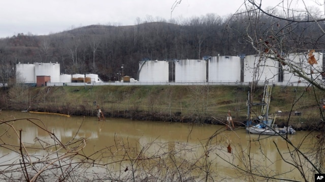 Workers inspect an area outside a retaining wall around storage tanks where a chemical leaked into the Elk River at Freedom Industries storage facility in Charleston, West Virginia, Jan. 13, 2014. 