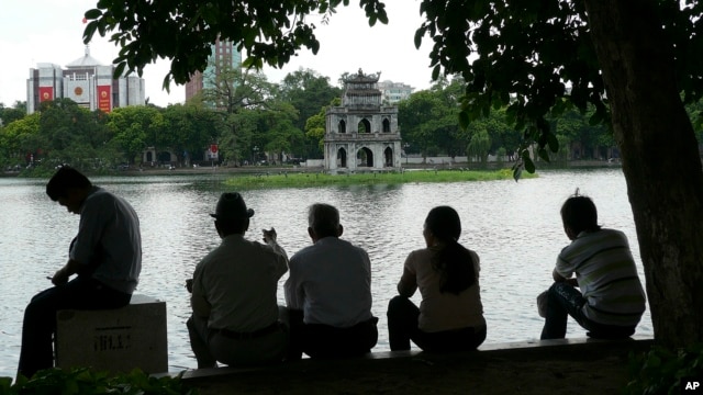 Người dân ngồi dưới bóng râm để tránh nắng tại Hồ Hoàn Kiếm, Hà Nội, Việt Nam.