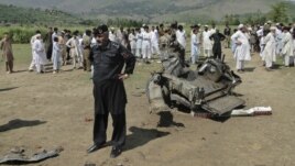 A security official and residents inspect the site of a bomb attack in the Lower Dir tribal area in Pakistan September 16, 2012. 