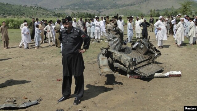 A security official and residents inspect the site of a bomb attack in the Lower Dir tribal area in Pakistan September 16, 2012. 