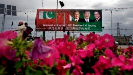 A Pakistani motorcyclist rides past a billboard showing pictures of Chinese President Xi Jinping, center, with Pakistan's President Mamnoon Hussain, left, and Prime Minister Nawaz Sharif welcoming Xi to Islamabad, Pakistan, April 19, 2015.