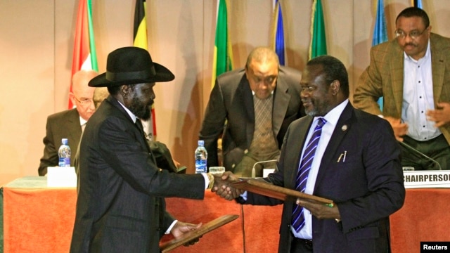 FILE - South Sudan's President Salva Kiir, left, and South Sudan's rebel commander Riek Machar exchange documents after signing a cease-fire agreement in Ethiopia's capital, Addis Ababa, Feb. 1, 2015.